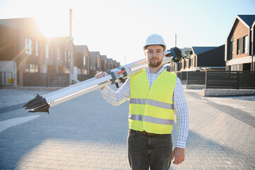 Engineer carrying surveying equipment at new construction site