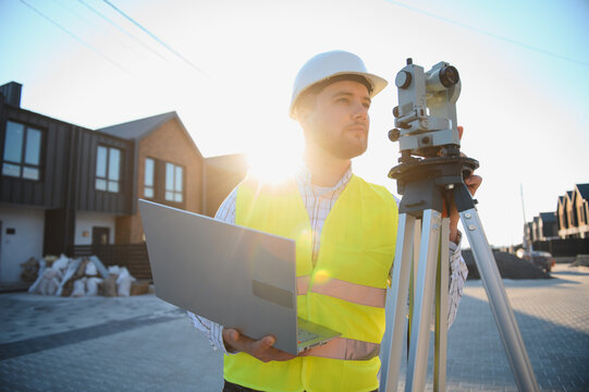 Surveyor using total station and laptop on construction site