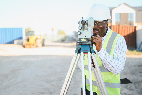 African american surveyor setting up total station at construction site