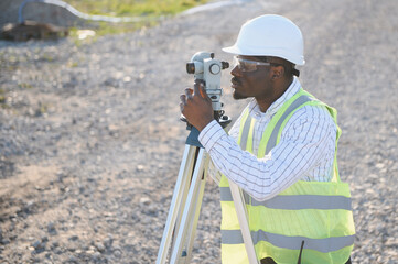 Obraz na płótnie Canvas African american land surveyor working with surveying equipment