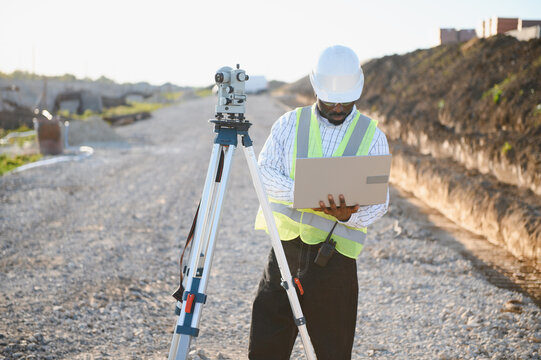 African american land surveyor using laptop at construction site