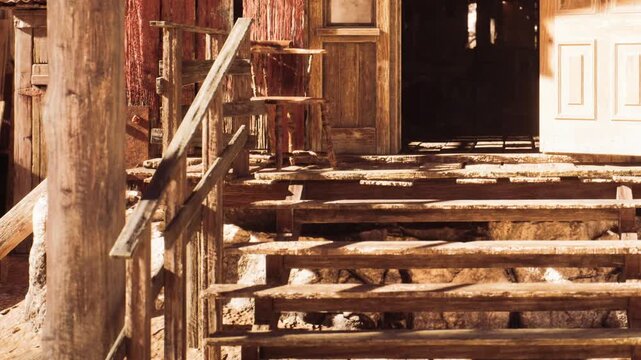 Wooden stairs are seen leading up to a door of an old building located in a deserted area. The structure shows signs of age and neglect, with simple wood materials.