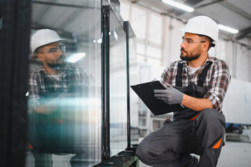 Plakat Worker performing quality control on window frames