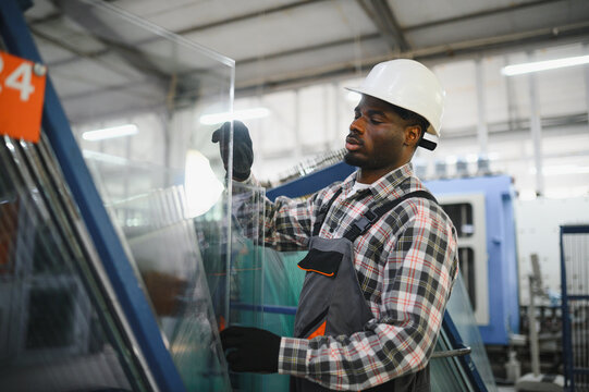 African american worker handling glass panel in factory