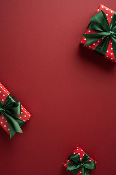 Merry Christmas gift boxes with green bows on red vertical burgundy background for Happy New Year celebration