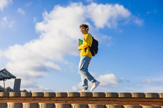 College student listening music while walking on campus rooftop