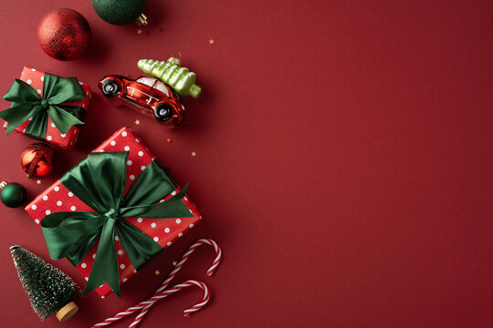 Merry Christmas gift arrangement with red and green presents, ornaments and candy canes for Happy New Year on burgundy backdrop