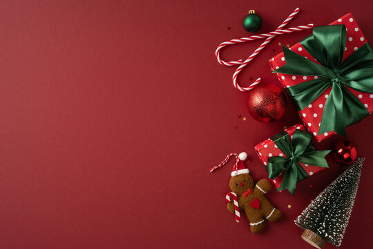 Festive Christmas presents with green bows, candy canes and gingerbread on red background