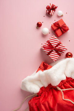 Merry Christmas and Happy New Year Santa Claus presents in a red velvet gift sack with ornaments on vertical pink background