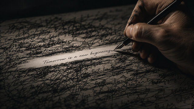 Hand writing the inspirational quote Tomorrow is a new beginning on a dark paper covered with scribbles, symbolizing hope, fresh start, optimism, future planning, and mindset shift   