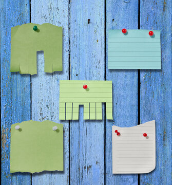 Various paper stickers and tear-off ads pinned to an old blue wooden board.