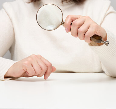 Woman holding magnifying glass over table, concept of truth seeking, problem solving