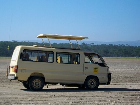 PARC NATIONAL DU LAC NAKURU, KENYA - 25 JANVIER 2010 : Minibus de safari blanc avec toit ouvrant stationn&eacute; dans la plaine aride du parc national.
