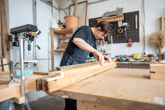 Carpenter comparing and adjusting wooden patch for old wooden frame in restoration workshop, craftsman precisely picking wood grain replacement part for ideal fitting, craftsmanship in handmade work