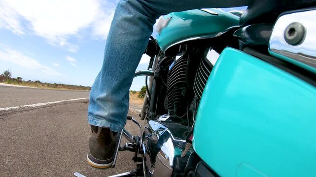 POV from the passenger footrest showing a biker mounting a custom motorcycle, starting the engine, raising the kickstand and engaging first gear with natural sounds.