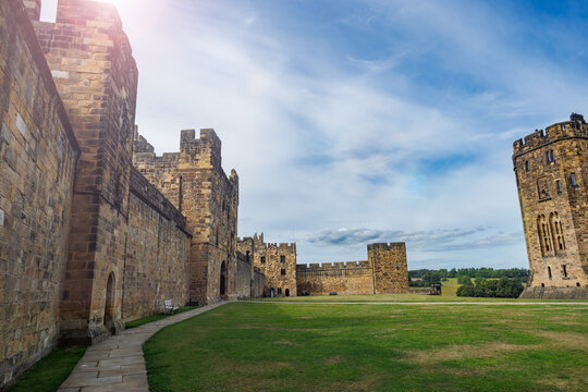 Medieval Alnwick castle walls and towers under blue sky, UK