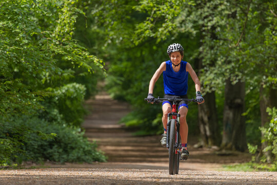 Teenager boy riding mountain bike along a forest trail outdoors