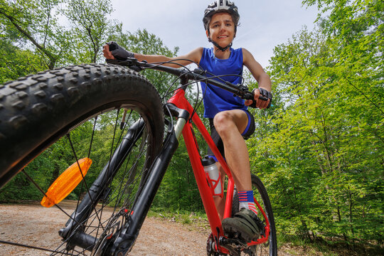 Young cyclist boy riding red mountain bike through forest trail