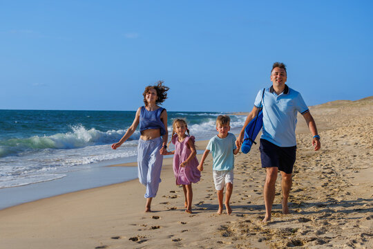 Family walking along sandy beach beside ocean waves