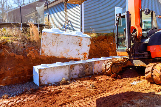 Excavator machine lifts large cement blocks of material at construction site for retaining walls