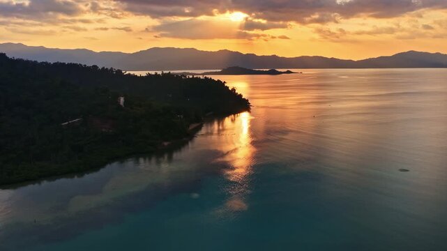 Aerial view of Port Barton Beach at sunset with calm waters and distant mountains in Mimaropa, Philippines.