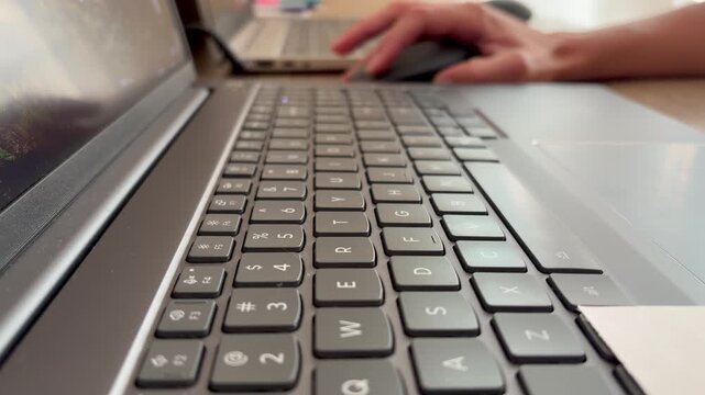 Hands typing on a modern laptop keyboard. Writing, programming, or working on a computer in daylight.