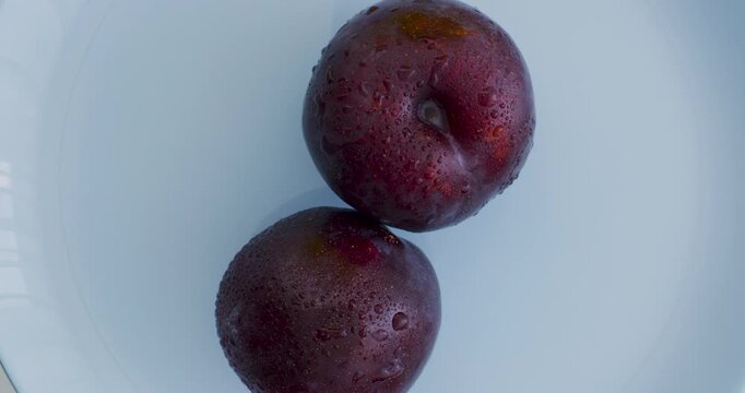 Ripe, juicy plums on a blue plate. Fruits and time of harvesting. Juicy plums sprinkled with water close up.	