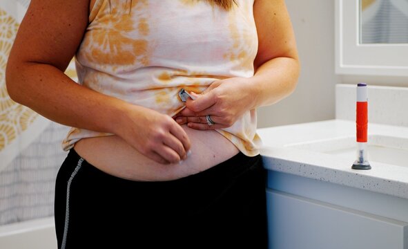Middle aged female providing GLP1 shot in stomach for weight loss, obesity, diabetes, weight management - Expensive pharmacueticals game changing meds