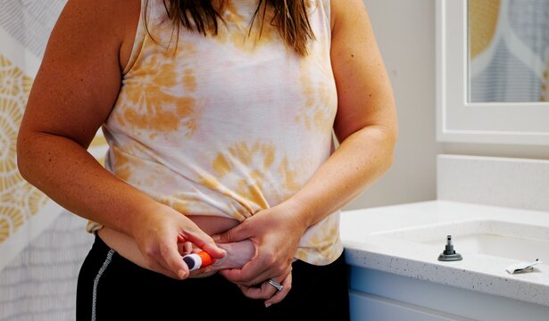 Middle aged female providing GLP1 shot in stomach for weight loss, obesity, diabetes, weight management - Expensive pharmacueticals game changing meds