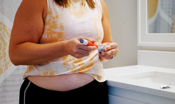 Middle aged female providing GLP1 shot in stomach for weight loss, obesity, diabetes, weight management - Expensive pharmacueticals game changing meds
