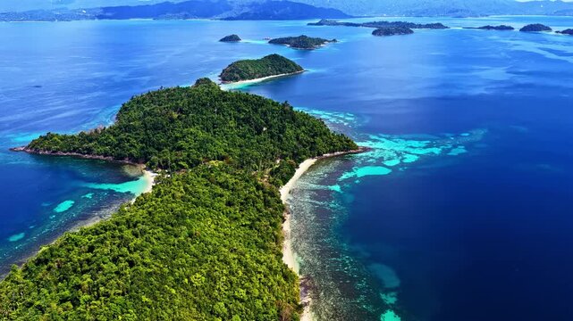Aerial view of Port Barton Beach islands with lush green vegetation and turquoise coral reefs surrounded by deep blue sea in Mimaropa, Philippines.