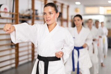 European women at group karate training, they try fighting stances. Young women came to a trial karate class © JackF