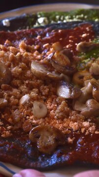 Close-up shot of fresh homemade Mexican antojitos topped with saut&eacute;ed mushrooms, cotija cheese, pork rinds and salsa