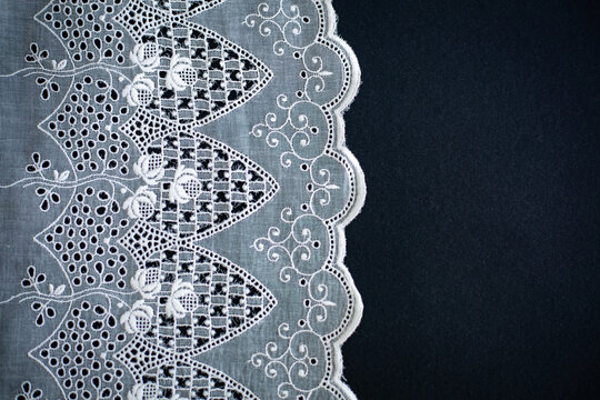 Lace pattern, detail of a tablecloth isolated on a black background. Artistic border. Handicraft, vintage. Hobby concept. Top view.