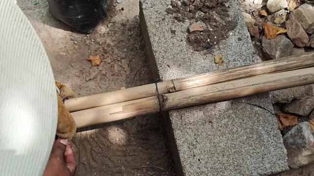 Handyman Securing Bamboo Stalks with Pliers and Steel Wire
