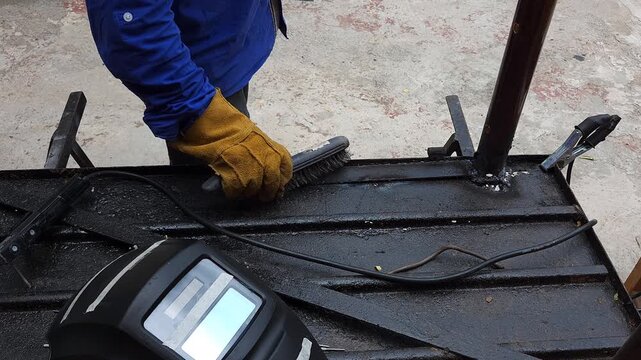 Handyman Scraping Slag Off Welded Joint Using Metal Wire Brush