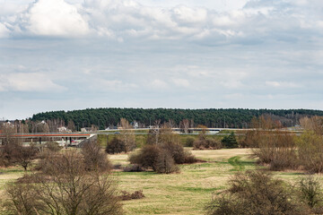 Most drogowy nad zieloną doliną na tle gęstego lasu sosnowego pod zachmurzonym niebem © mbugajsky