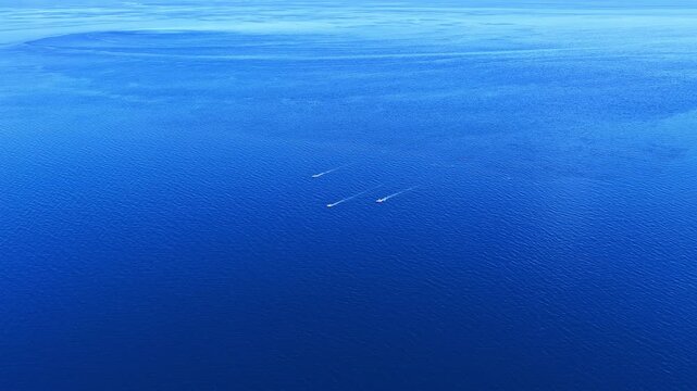Aerial view of three small boats leaving wakes on the deep blue ocean near Limasawa, Eastern Visayas, Philippines.