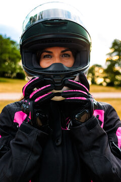 Female biker wearing full face helmet, gloves, and protective jacket