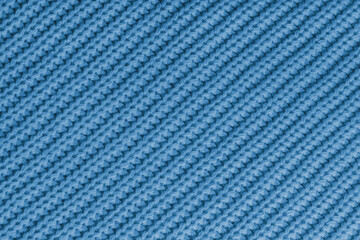 Close up, macro of blue knitted fabric texture with visible diagonal yarn stitches and soft wool pattern. Cozy textile backdrop, cloth background, fashion wallpaper, winter clothing concepts © katyamaximenko