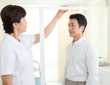 Nurse measuring the height of an adult man with a height stand at a health checkup