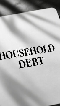 Close-up of a printed document featuring the words household debt, with soft shadows and a minimalist financial concept.