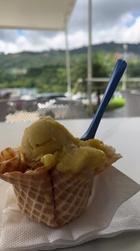 Melting mango ice cream in edible waffle cone bowl outdoors