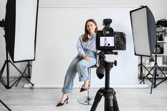 Professional photography session, woman posing for portrait in studio with camera on tripod and lighting equipment for creative content production