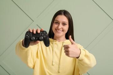 Gaming and entertainment, happy young woman holding a video game controller and giving a thumbs up gesture for leisure and digital lifestyle © Pixel-Shot