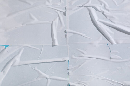 Urban street art background, white glued paper texture with wrinkles and folds on a blue wall for poster mockup and graphic design overlay