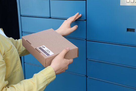 Parcel delivery and e-commerce logistics, person picking up a cardboard package from an automated blue locker station for contactless shipping retrieval