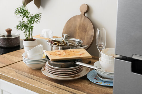 Household chores and domestic burnout, stack of dirty dishes and messy kitchen counter after dinner party with unwashed cookware and food residue