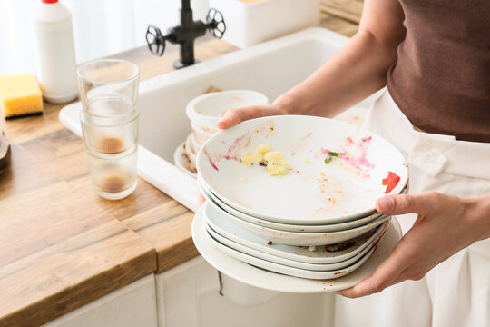 Household chores and domestic burden, person holding a stack of dirty dishes in a kitchen sink for cleaning and hygiene maintenance