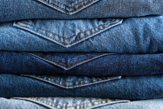 Fashion retail and sustainable clothing, stack of folded blue denim jeans with visible pockets and stitching in a textile store or wardrobe